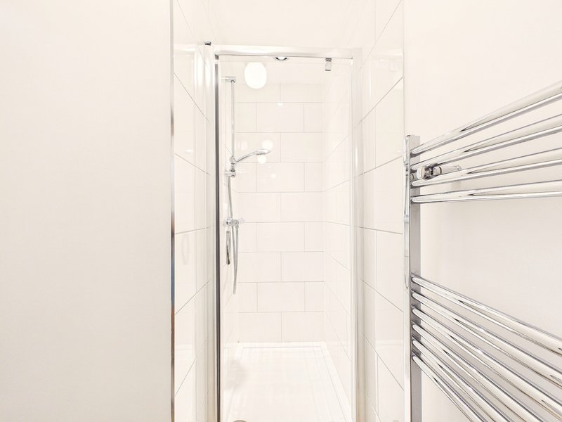 Modern bathroom with walk-in shower enclosure, white tiles and heated towel rail