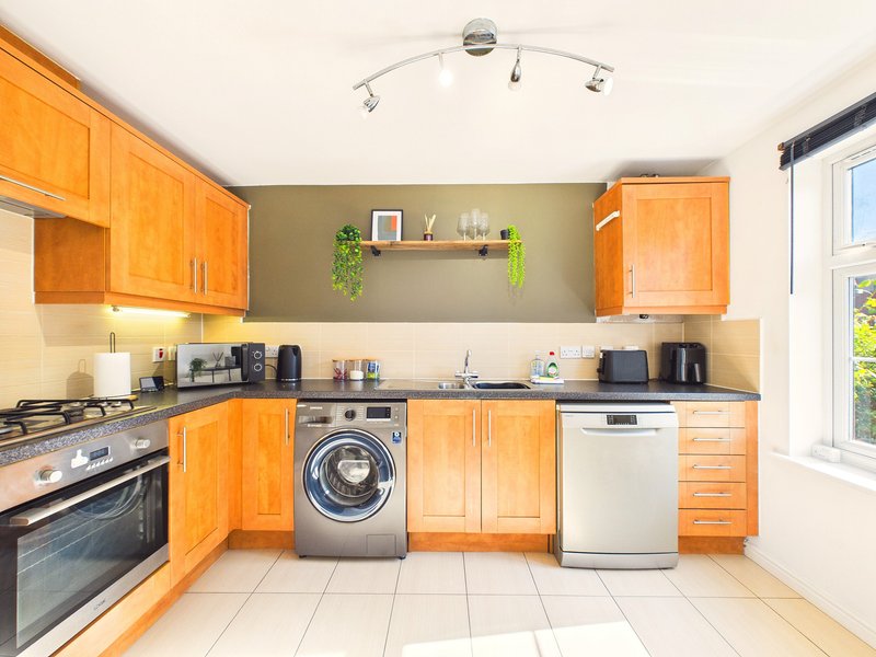 Modern kitchen with orange wooden cabinets, stainless steel appliances and white tile flooring