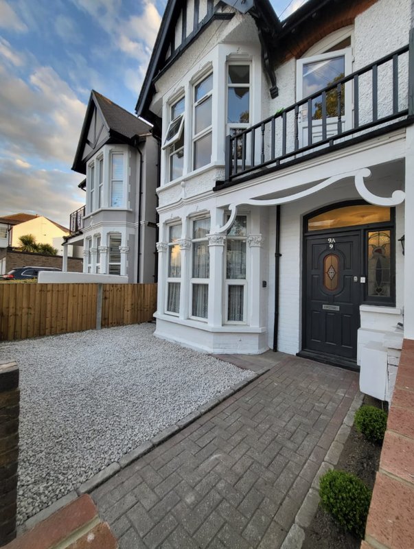 Modern Tudor-style house with black and white exterior, driveway, and front entrance with potted plants