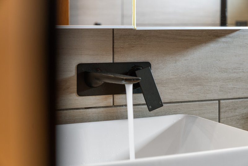 Modern bathroom sink with black wall-mounted faucet and white basin