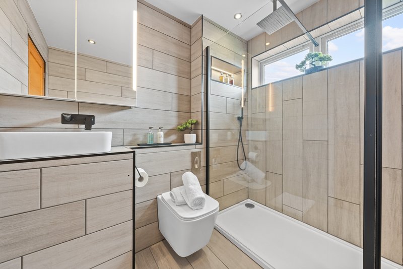 Modern bathroom with walk-in shower, white toilet, vanity sink and light wood tiling