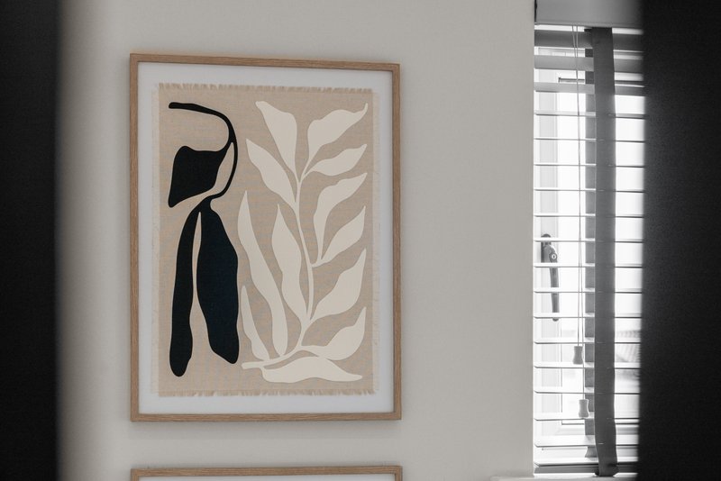 Modern abstract art print on white wall with wooden frame and shuttered window