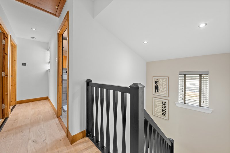 Landing area with black stair railing, wooden doors, and framed wall art
