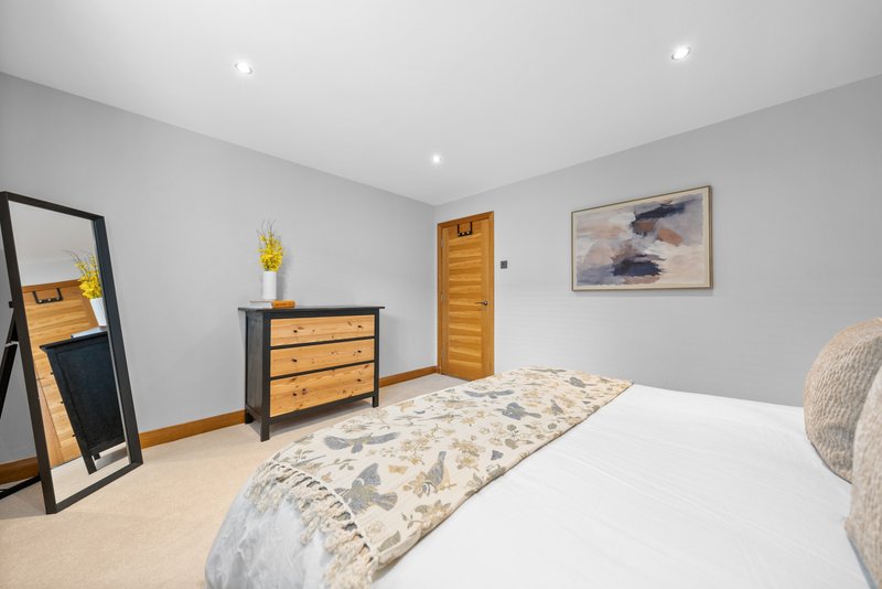 Modern bedroom with double bed, wooden furniture, mirror, and framed artwork on walls