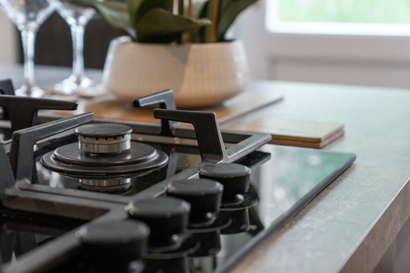 Kitchen countertop with gas cooktop, potted plant, glasses and decorative items