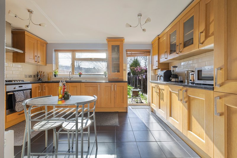 Modern kitchen with wooden cabinets, white subway tile backsplash, dining table and garden view