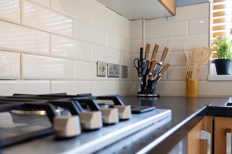 Modern kitchen countertop with knife block, utensil holder, potted plant and white subway tile backsplash