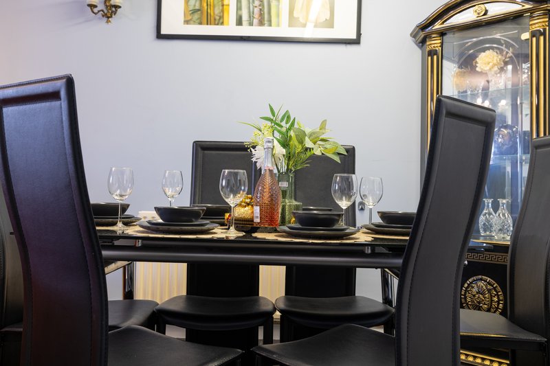 Formal dining room with black table, upholstered chairs, glassware and floral centerpiece