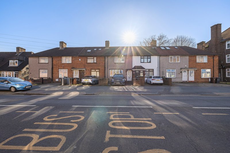 Brick terraced houses with street frontage, parked cars and clear sky