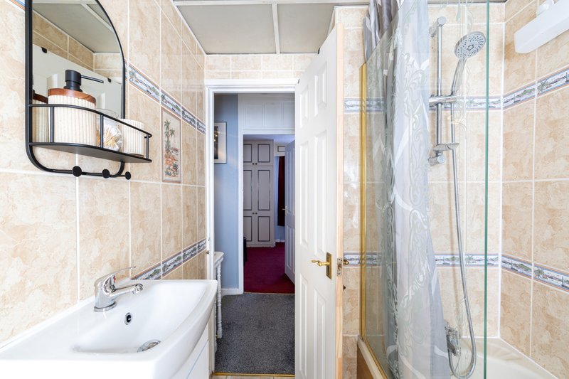 Bathroom with sink, mirror, shower enclosure and tiled walls