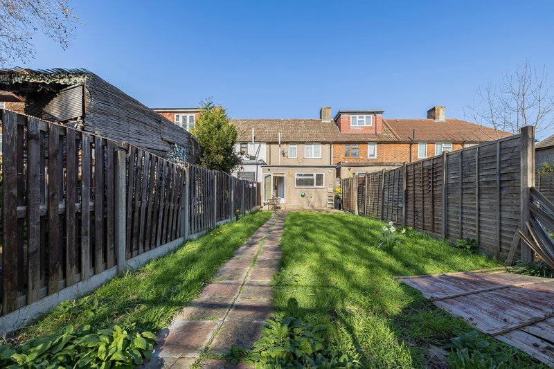 Narrow garden with fencing, paved pathway, and period terrace houses beyond
