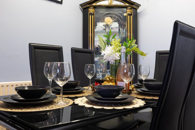 Formal dining table set with black chairs, place settings, wine glasses and fresh flower centerpiece