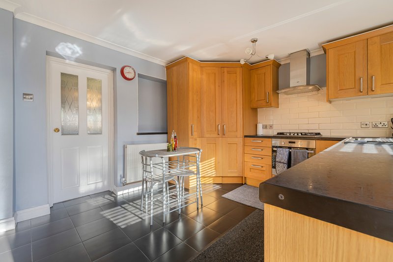 Modern kitchen with wooden cabinets, black countertop, breakfast bar seating and door to garden