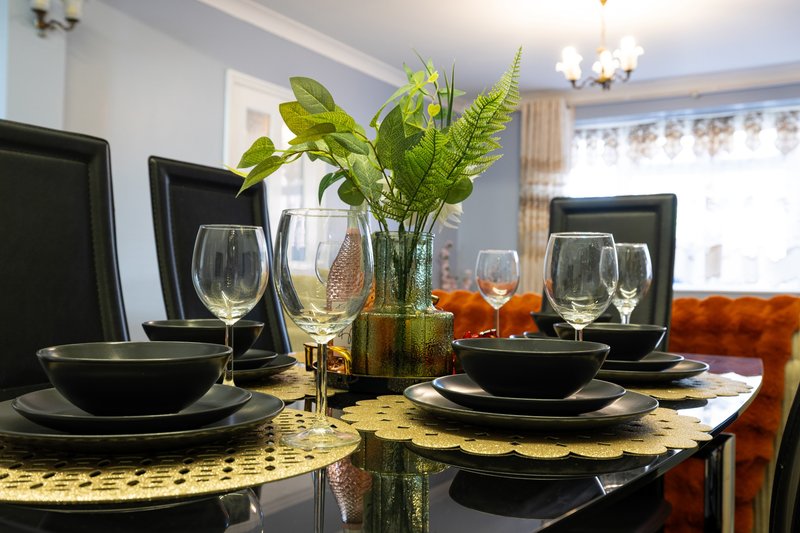 Dining table set with black plates, wine glasses, and fresh green plant centerpiece