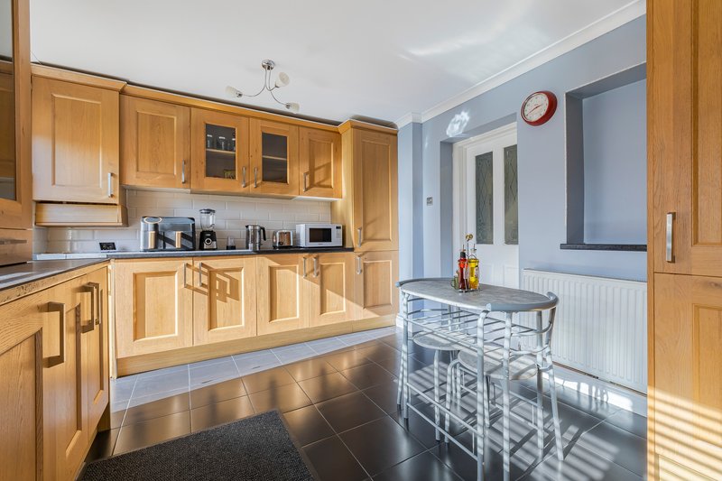 Modern kitchen with wooden cabinets, stainless steel appliances, and dining counter with bar stools