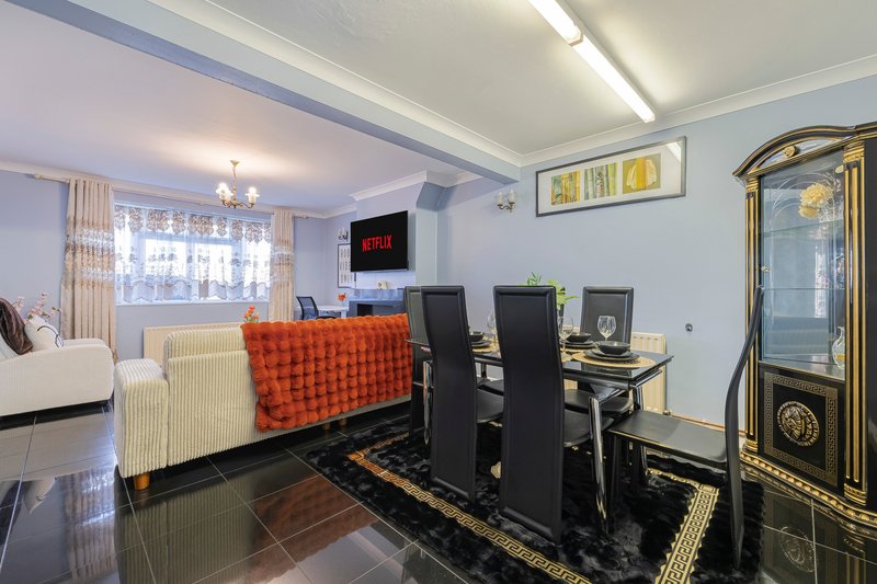 Open-plan living and dining area with sofa, dining table, chairs, and entertainment unit