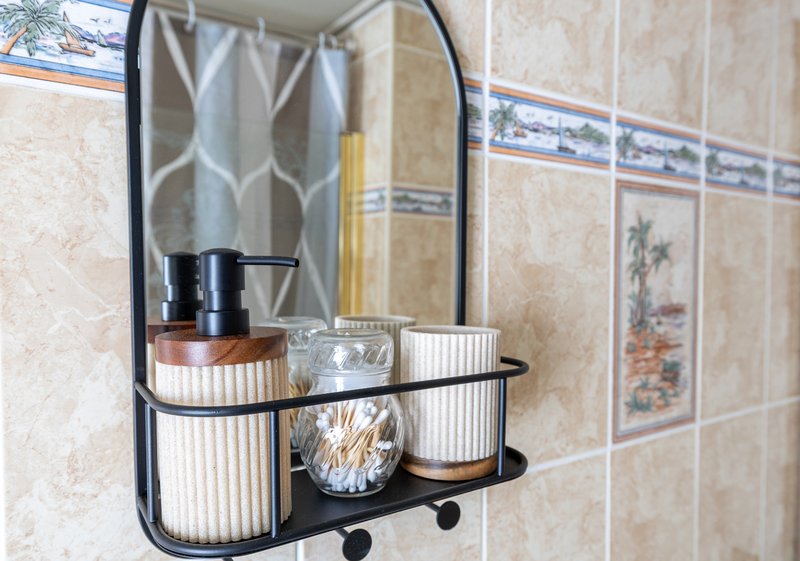 Bathroom shelf with soap dispenser, toothbrush holder, and decorative items above sink