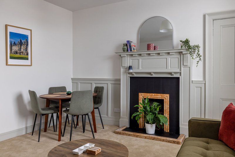 Living room with fireplace, dining table, chairs, round coffee table and framed artwork