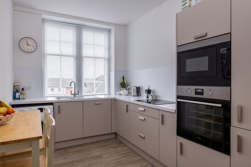 Modern kitchen with grey cabinetry, built-in oven and microwave, window overlooking street