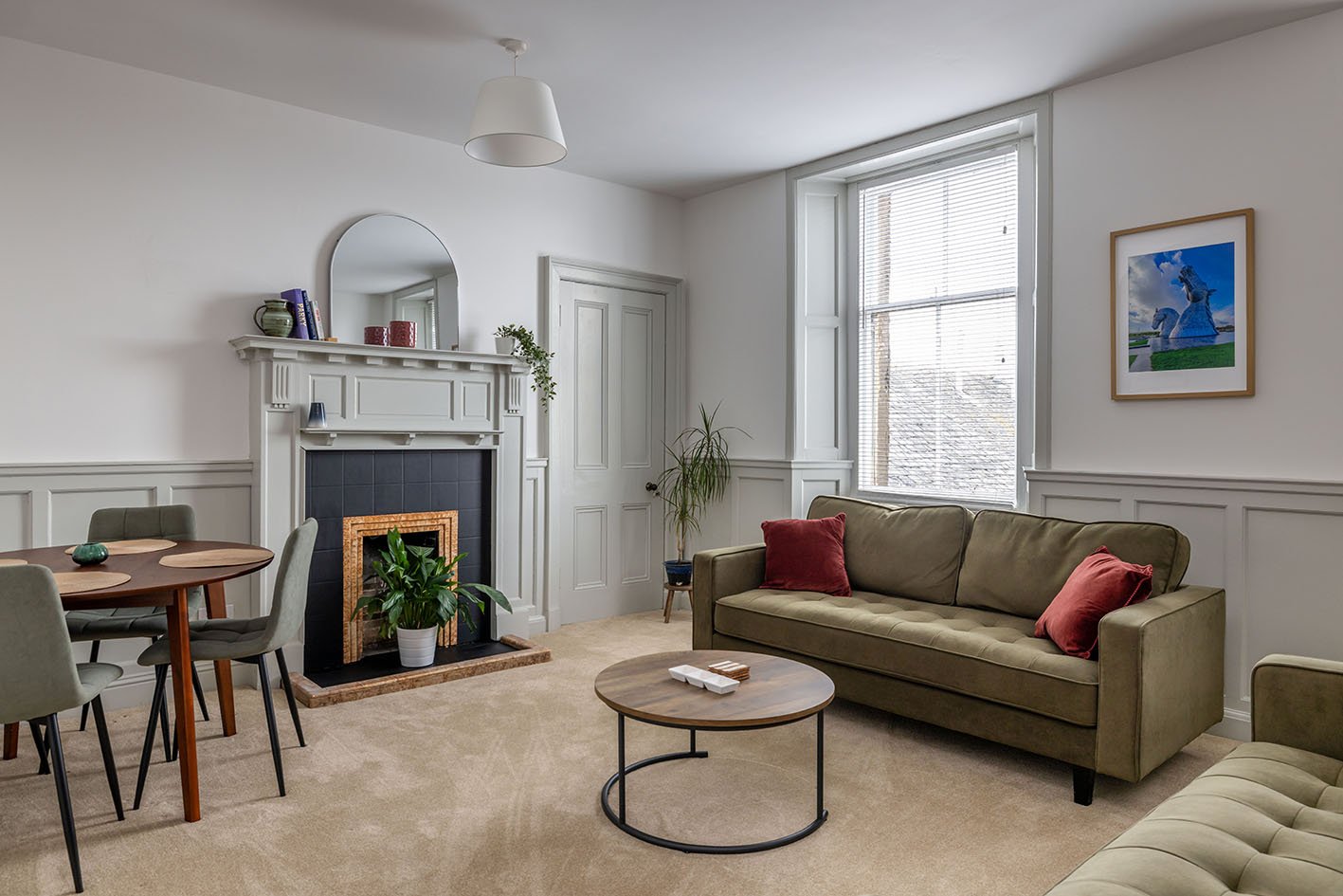 Modern living room with fireplace, green sofa, round coffee table and dining area