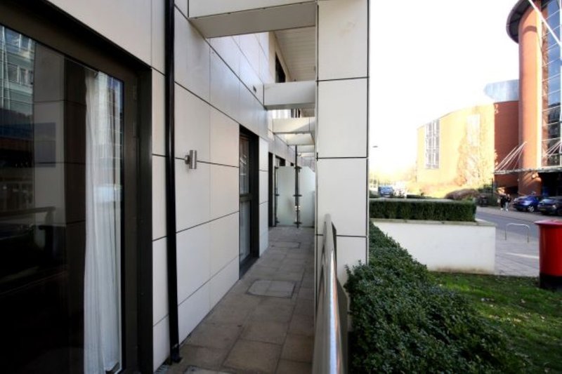 Modern covered walkway with white walls, black doors, and street view beyond