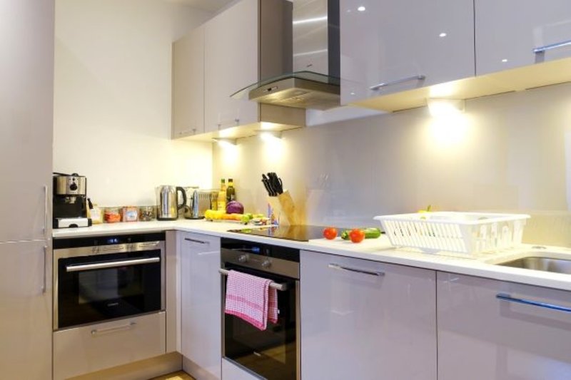 Modern kitchen with white cabinets, stainless steel appliances, and countertop with fresh produce