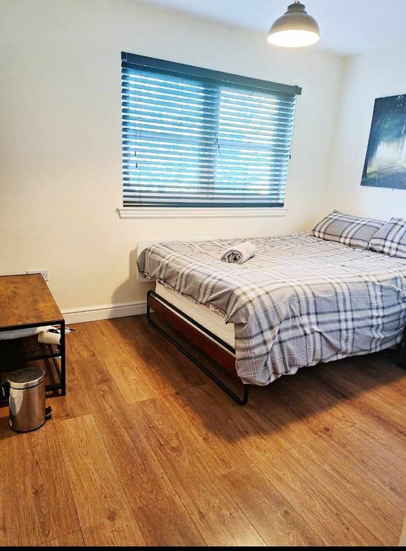 Bedroom with double bed, wooden floor, blue blinds and pendant light