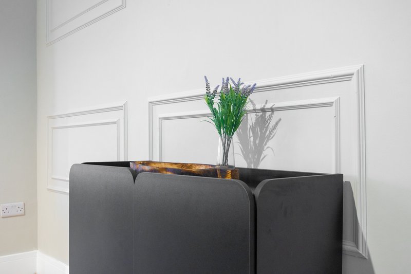 Modern black sofa with green plant arrangement and decorative item on top