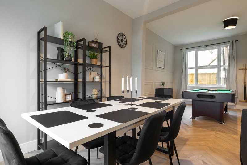 Modern open-plan dining and living room with black and white table, shelving unit, and garden views