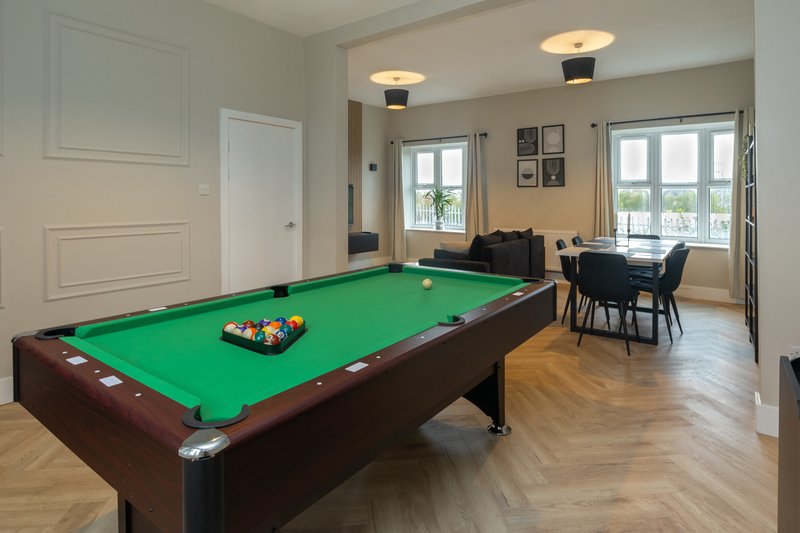 Games room with pool table, dining table, and seating area with large windows
