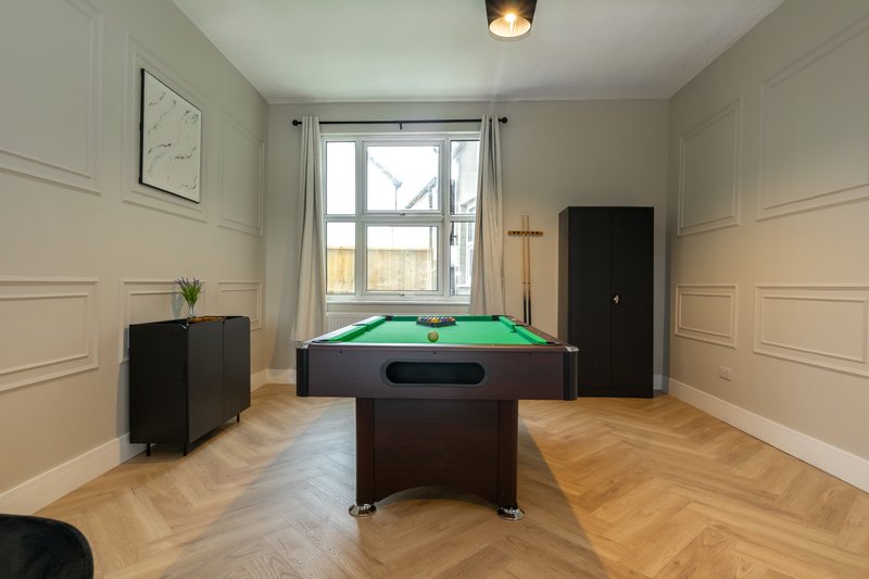 Recreation room with pool table, black storage cabinet, wooden flooring and large window