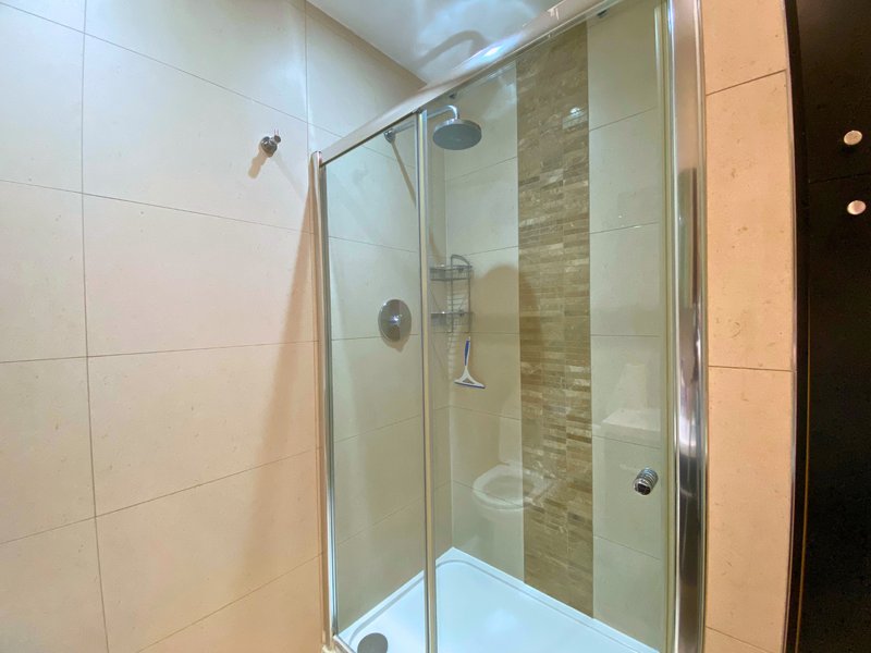 Modern bathroom with enclosed shower cubicle, beige and brown tile walls, chrome fixtures