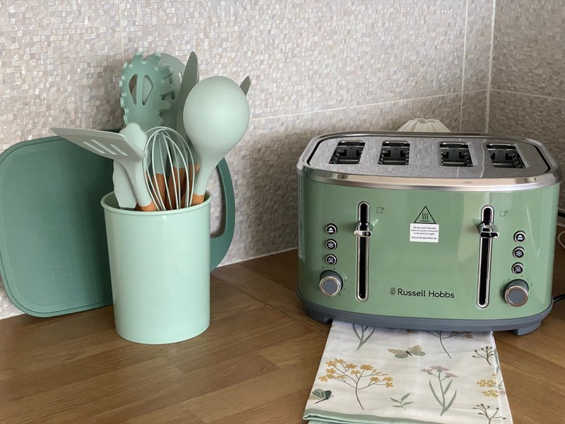 Kitchen counter with green toaster, utensil holder with cooking tools, and decorative items