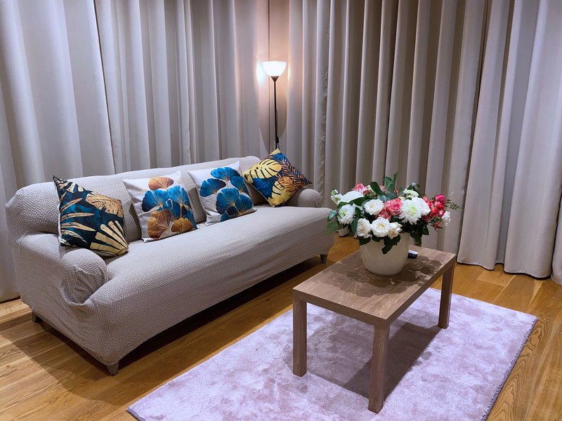 Modern living room with cream curved sofa, decorative pillows, wooden coffee table and fresh flowers