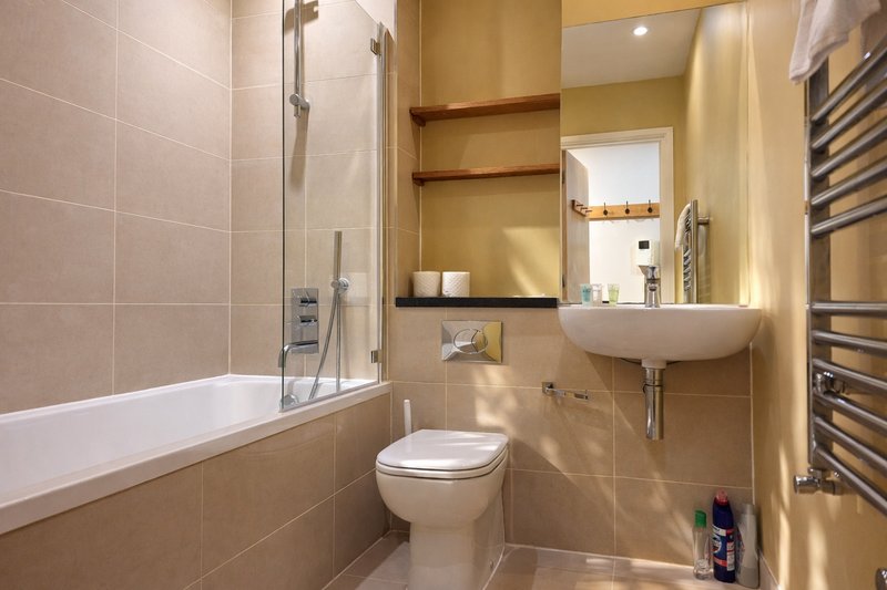 Modern bathroom with bathtub, toilet, sink, mirror and heated towel rail
