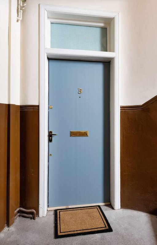 Hallway with blue door, white frame, wood paneling and coir doormat