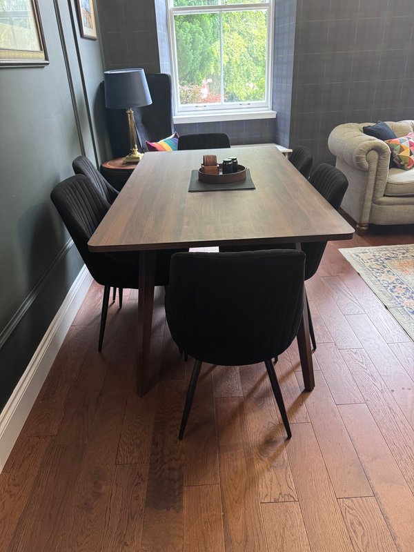 Dining room with wooden table, black chairs, window view and upholstered sofa