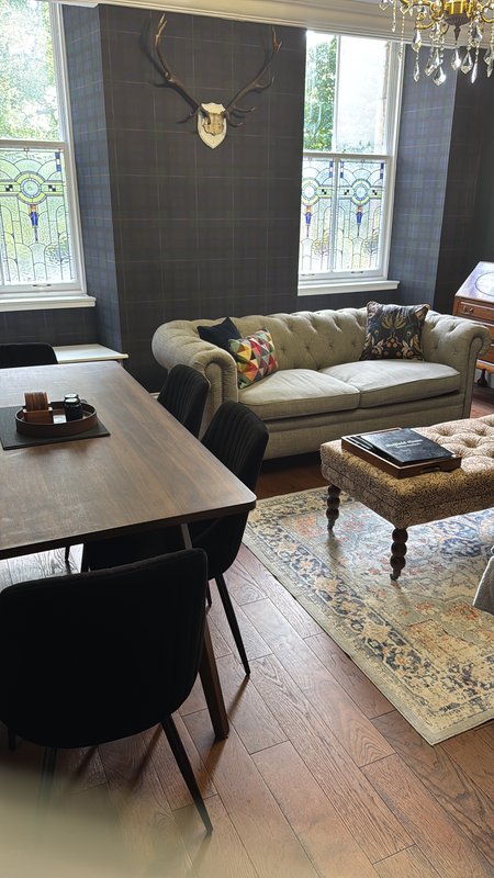 Living room with sofa, dining table, chair, and mounted deer head above fireplace