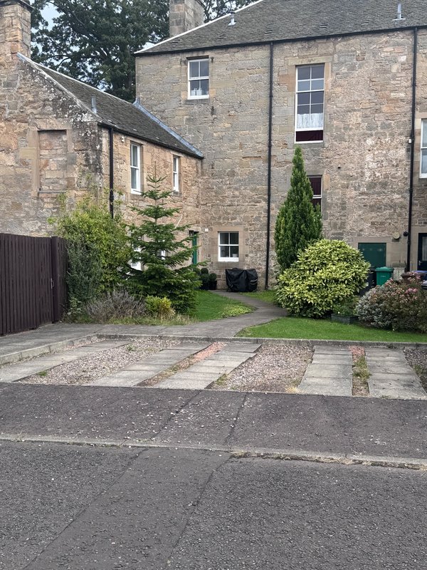 Stone terraced house with driveway, garden, and manicured landscaping