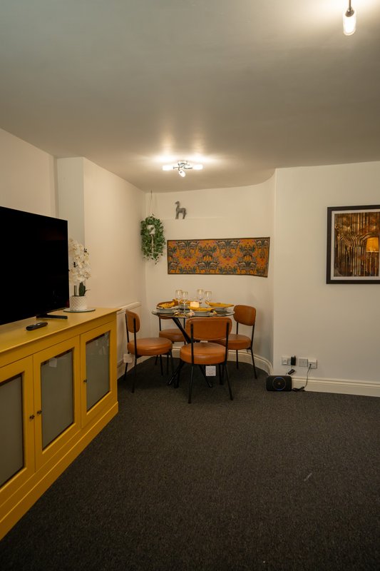 Furnished living room with dining table, wooden cabinet, TV, and framed wall art