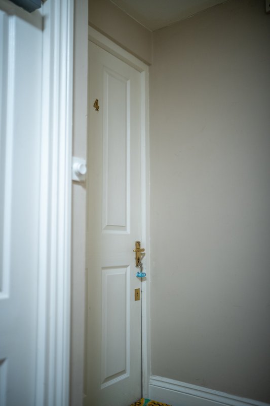 Hallway with white panelled door, brass handles, and cream-coloured walls