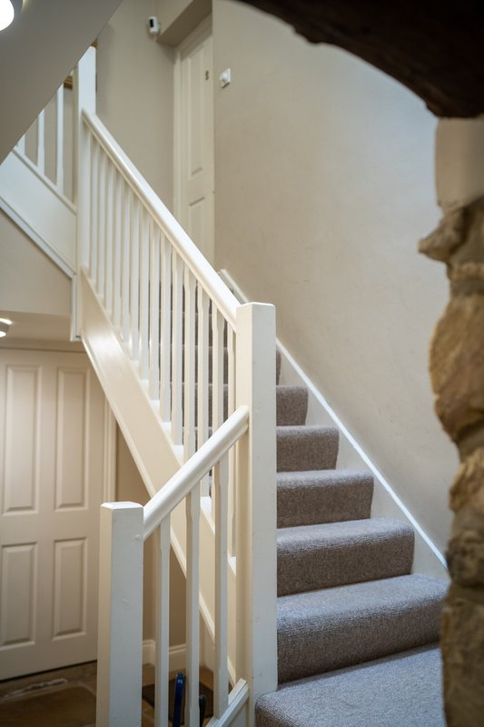 Bright staircase with white railing, gray carpeted steps and wooden door