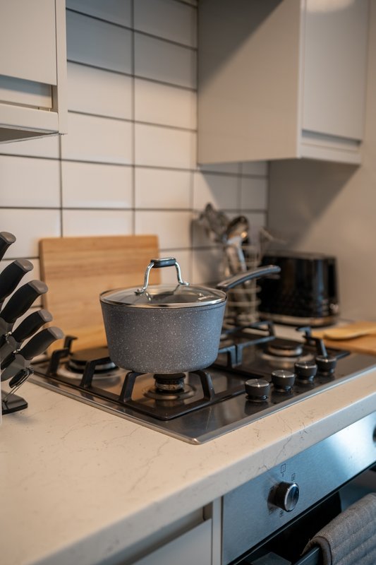 Modern kitchen with pot on stovetop, white subway tile backsplash and wooden utensil holder