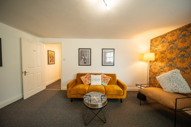 Modern living room with mustard sofa, patterned accent wall, floor lamp and round coffee table