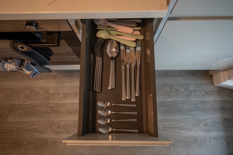 Kitchen drawer open showing organized cutlery and utensils in wooden organizer