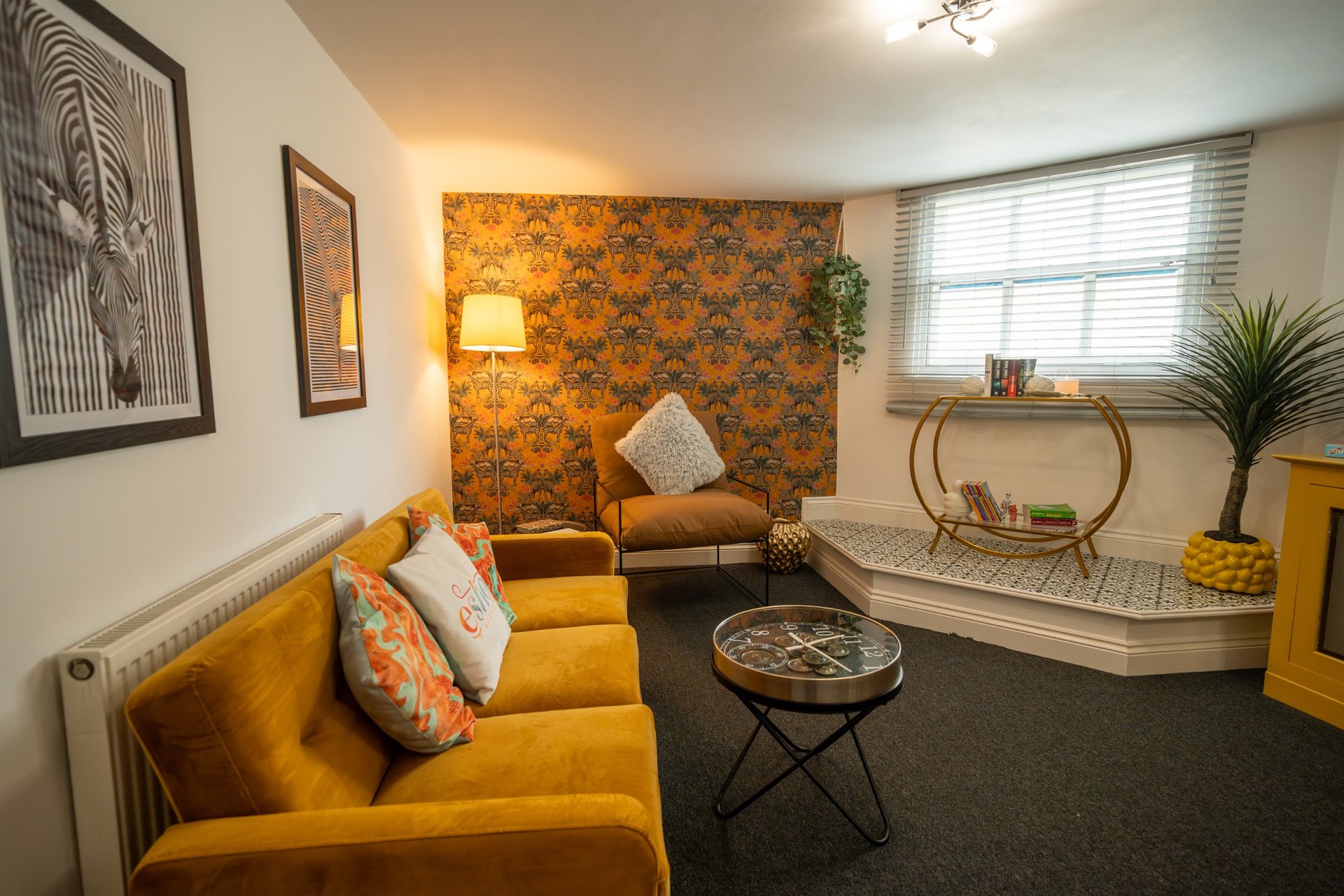Bright living room with yellow sofa, patterned accent wall, and modern furnishings