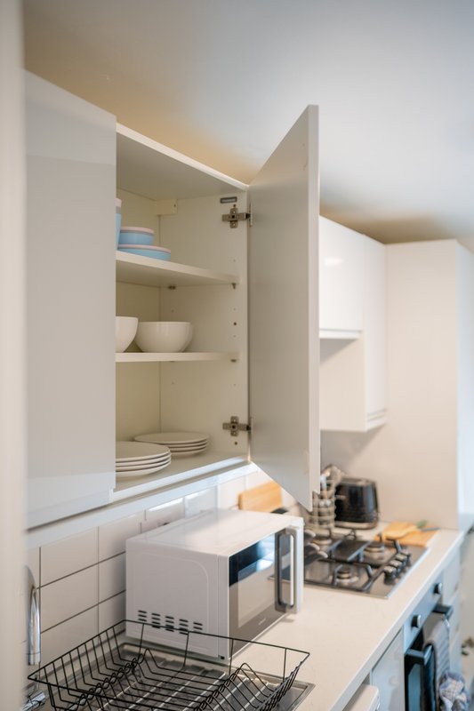 Kitchen cabinet open showing shelves with dishes and tableware inside