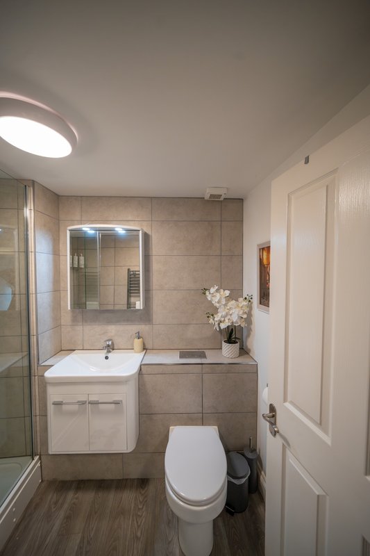 Modern bathroom with white vanity, mirror, toilet, shower enclosure and tiled walls