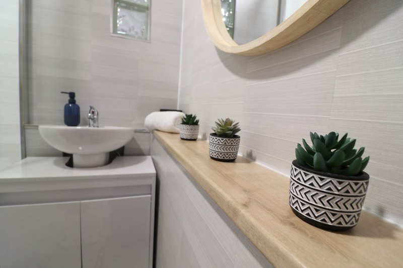 Modern bathroom with white subway tiles, wooden vanity, sink, mirror and potted succulents
