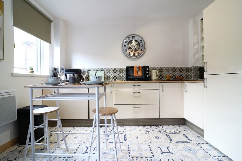 Modern kitchen with cream cabinets, patterned backsplash, wall clock, dining table and chairs